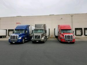 red, black and blue truck lined up at facility
